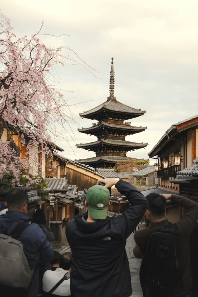 Tourists taking photos near Yasaka Pagoda in Kyoto during cherry blossom season